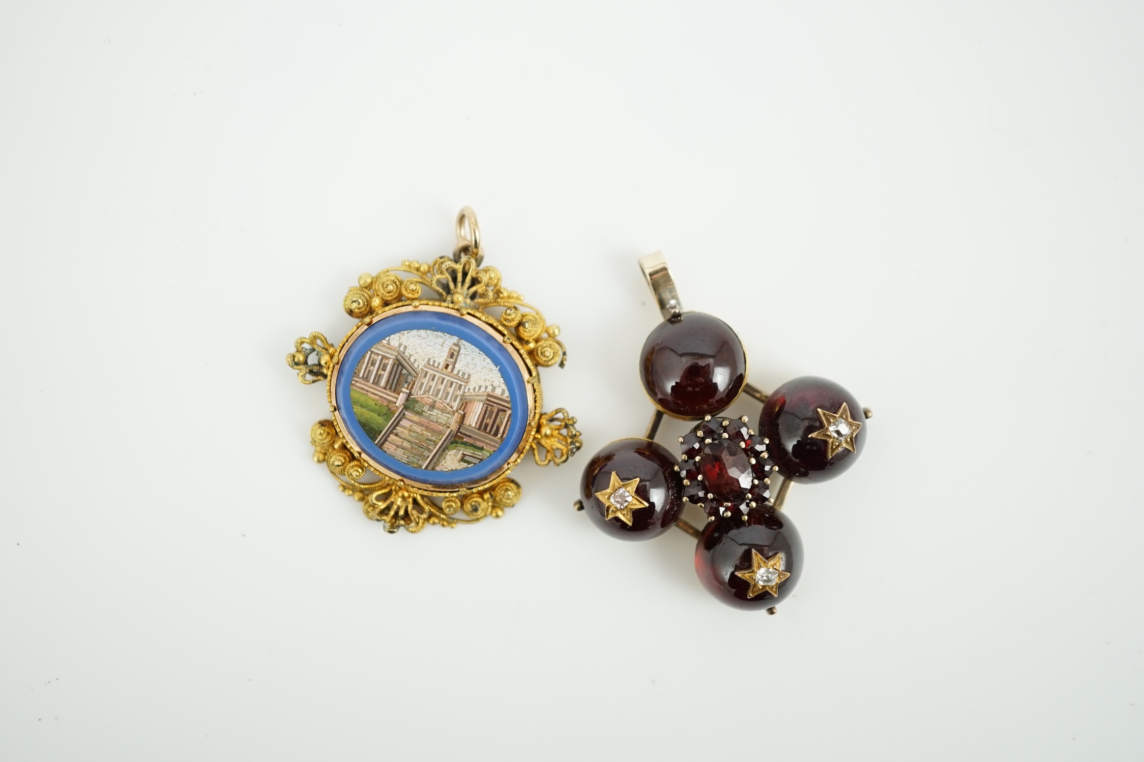 A 19th century gilt metal mounted micro mosaic pendant, 32mm, together with a similar cabochon garnet and diamond set quatrefoil pendant.